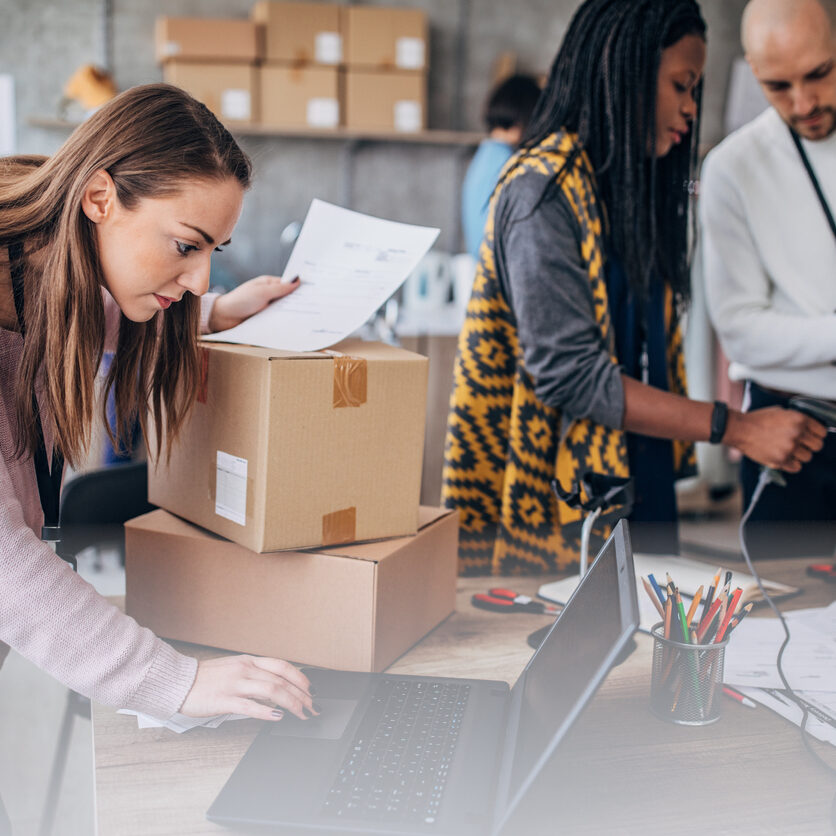 Multi-ethnic group of people, men and women arranging customers orders for drop shipping in warehouse.